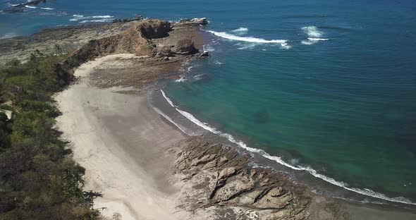 Aerial drone view of the beach, rocks and tide pools in Playa Palada, Guiones, Nosara, Costa Rica