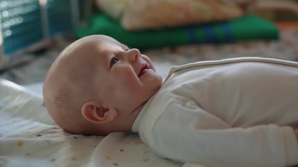 A Cute Baby Lies on His Back Smiling Cheerfully and Waving His Arms