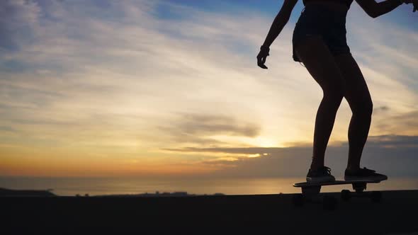 Silhouette of a Skateboarder Against the Sunset Sky in Slow Motion Steadicam Shot