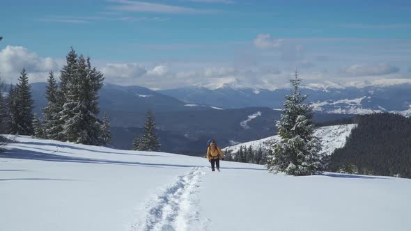 A Man with a Backpack Travels in the Mountains in Winter