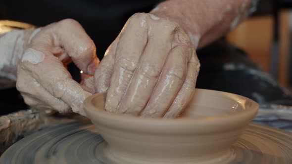 Close-up of Adult Man's Hands Shaping Clay Into Beautiful Hand-made Bowl on Throwing-wheel