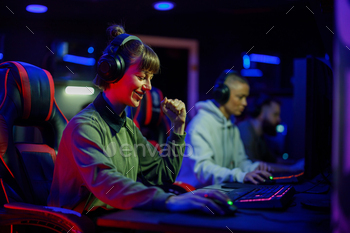 Woman gamer in a gaming club celebrating victory while playing a video game