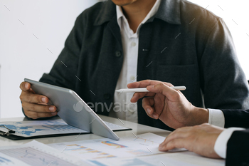 Business partnership coworkers using a tablet to chart company financial statements report