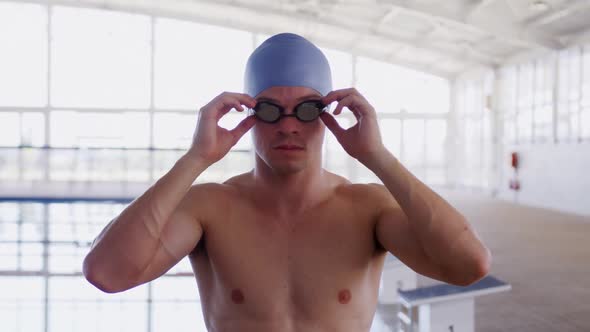 Swimmer taking off his pool goggles and looking at camera