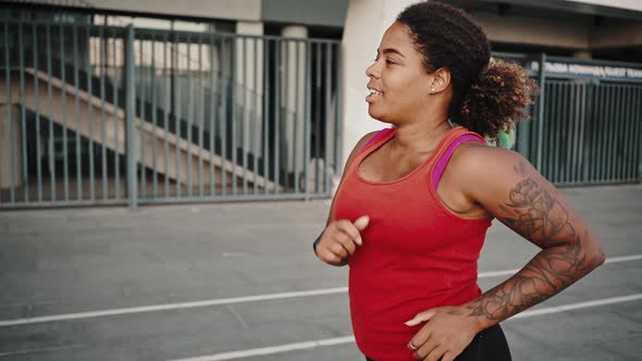 Young African American Woman Sprinter Running Outdoors Near Stadium Preparing for Marathon