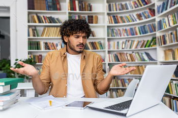 Confused student with laptop seeking help in a library