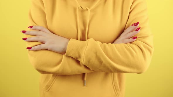 Body Part of Young Woman with Arms Crossed on Yellow Background