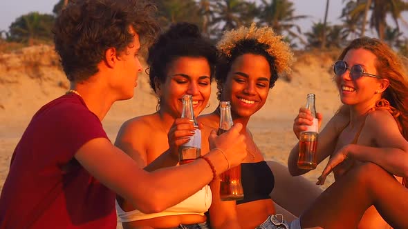 Afro American  Indian and Caucasian Group Drinking Lemonade on the Beach at Sunset