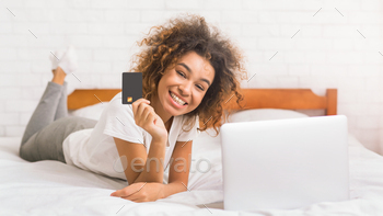 African-american woman doing online shopping in the bedroom