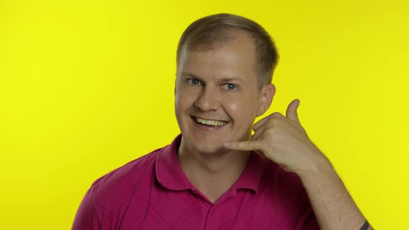 Portrait of Man Posing in Pink T-shirt. Happy Guy Asking To Call Him, Shows the Phone with His Hand