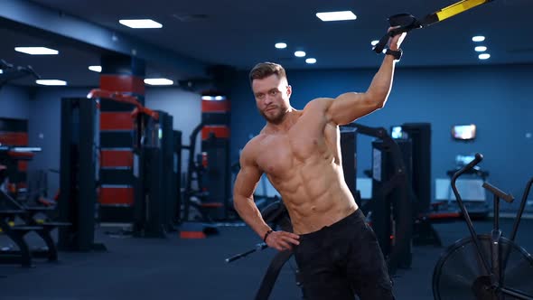 Strong handsome fitness trainer trains with a rope for side muscles.