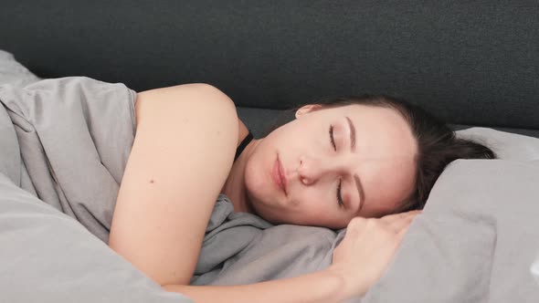 Charing female lying on bed with closed eyes, close up.