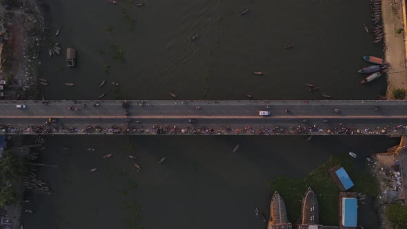 Aerial top down bridge with vehicle and people over a river. Establishing Drone descending shot