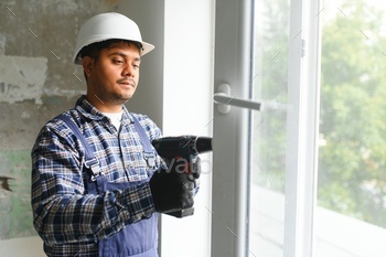Indian service man installing window with screwdriver