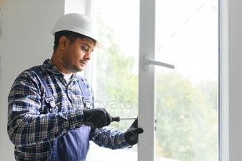 Indian service man installing window with screwdriver
