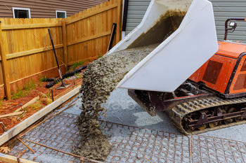 Wet cement is poured into framework using a self dumping track concrete buggy during construction of