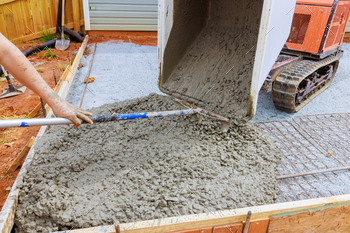 Self dumping track concrete buggy is used to pour wet cement into a framework during foundation