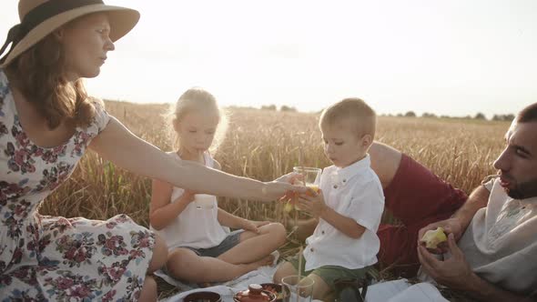 Mom Serves Son Juice in a Glass While His Older Sister Drinks Milk and the Family Eats Healthy Food