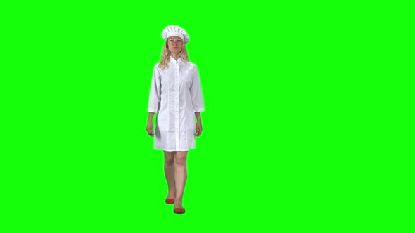 Blonde Cook Chef in White Uniform and Hat Going Against a Green Screen. Slow Motion