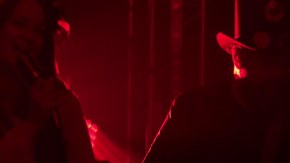 An Expressive Performance By a Female Vocalist of a Rock Band in a Dark Smoky Bar with a Red Light