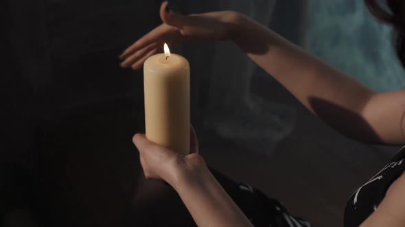 Woman Performing Esoterical Ritual of Purification. Fortune-teller Moving Hand Around Candle Sitting
