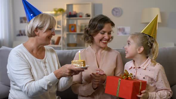 Young Woman Blowing Birthday Candle, Receiving Presents From Loving Family