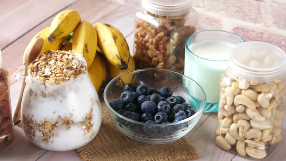 Fresh Blue Berry in Bowl with Banana Milk and Almond on Table