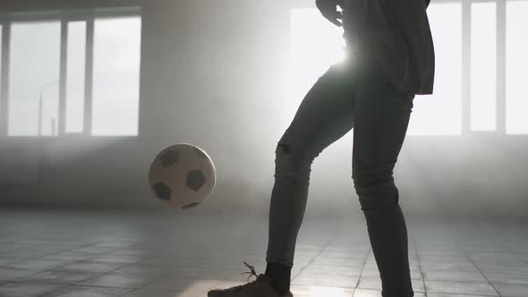 A Closeup Black Man Juggles a Soccer Ball in the Sunlight in the Garage