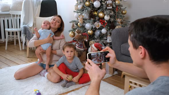 Father Photographing Family By Phone at Christmas