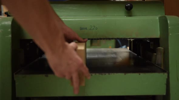 Carpenter Using Machine for Planing a Piece of Wood