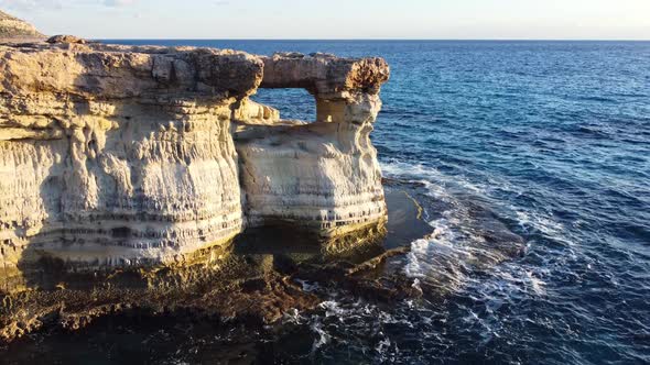 Flying Over Rocky Coastline Alongside Cliffside with Blue Mediterranean Sea Ocean Water Towards the