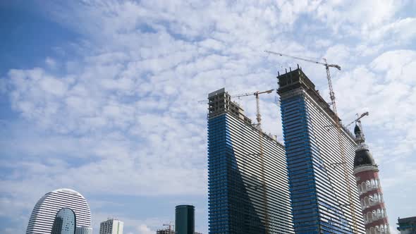 Construction of a Modern Skyscrapers Using Tower Cranes. Timelapse. Moving Clouds on Blue Sky