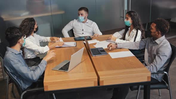 Multiracial Employees in Mask Sit in Conference Room Discuss Project Colleagues Actively Argue