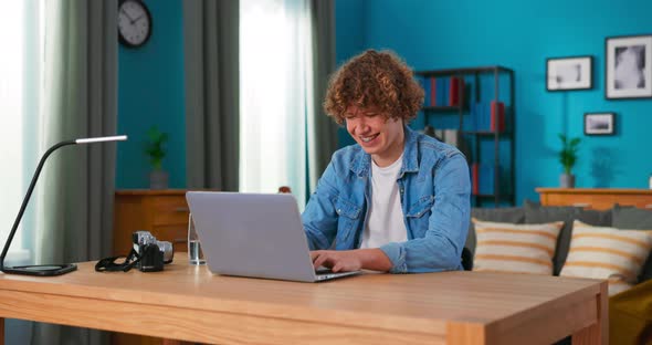 Handsome Caucasian Boy Working on Laptop Computer While Sitting on a Chair in Stylish Cozy