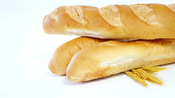 Baguettes with wheat on white background