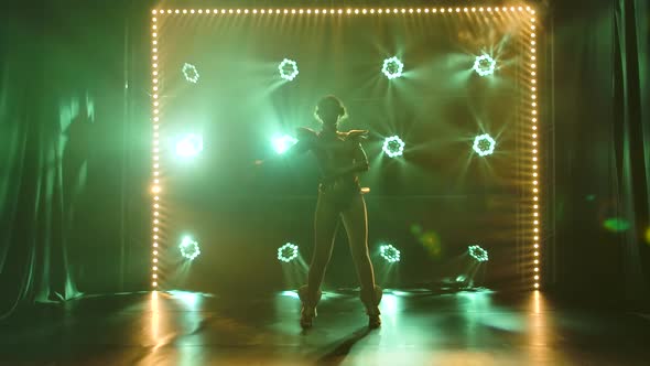 Silhouette of Dancing Young Women on Stage in a Dark Studio with Smoke and Neon Lighting