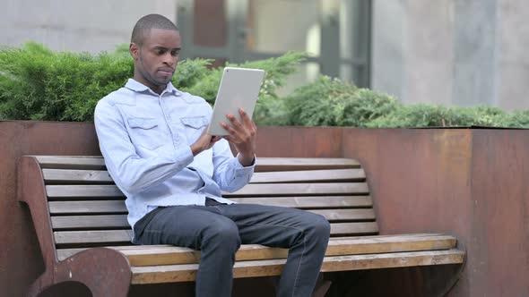 Outdoor Sitting Young African Man Using Tablet