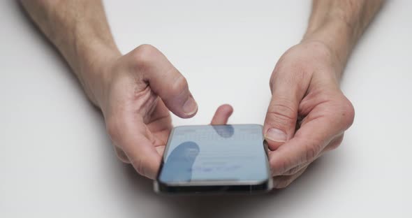 The Person Considers the New Device Hands are Holding the Smartphone on White Table Background