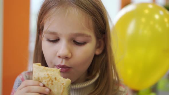 a Kid Girl Eats a Stuffed Pancake in a Cafe