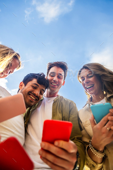 Young people using mobile phone device standing in circle outdoors