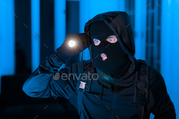 Burglar man with a flashlight searching intensely