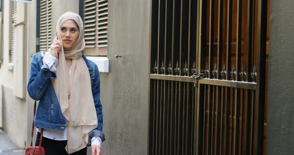 Woman in hijab talking on mobile phone while walking on the street