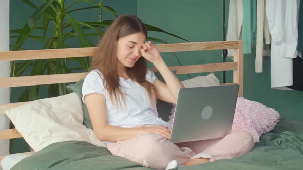 A Young Woman Feels Headache Eye Strain While Working on Laptop in Bed at Home