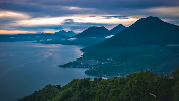 Aerial view of Lake atitlan in Guatemala during Sunrise, Errupting Volcano in Background, flying sid