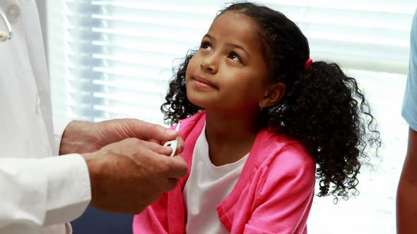 Male doctor interacting with patient while checking temperature on thermometer