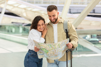 Young Couple Examining Map At Urban Transport Hub Or Airport
