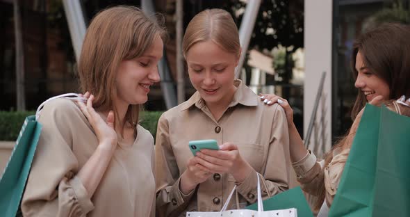 Beautiful Women Holding Shopping Bags Laughing While Standing at Street. Attractive Millennial Girl