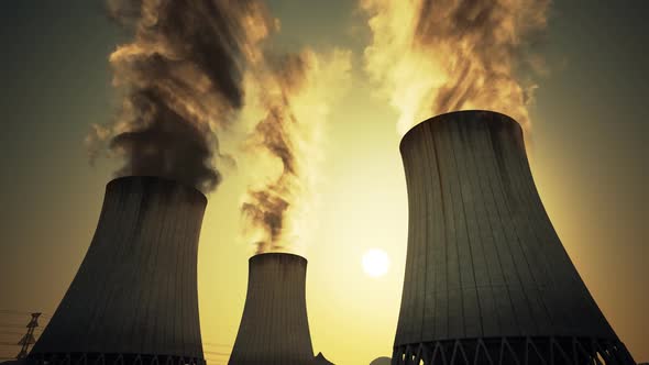 Nuclear power plant steaming cooling towers. Air pollution power station.Sunset