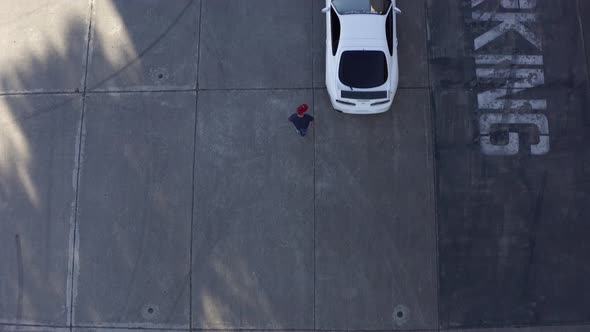 Aerial: guy walking towards white Toyota Supra,ing forward drone.