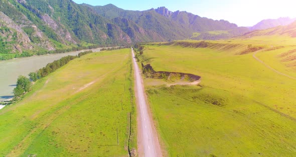 Aerial Rural Mountain Road and Meadow at Sunny Summer Morning. Asphalt Highway and River.